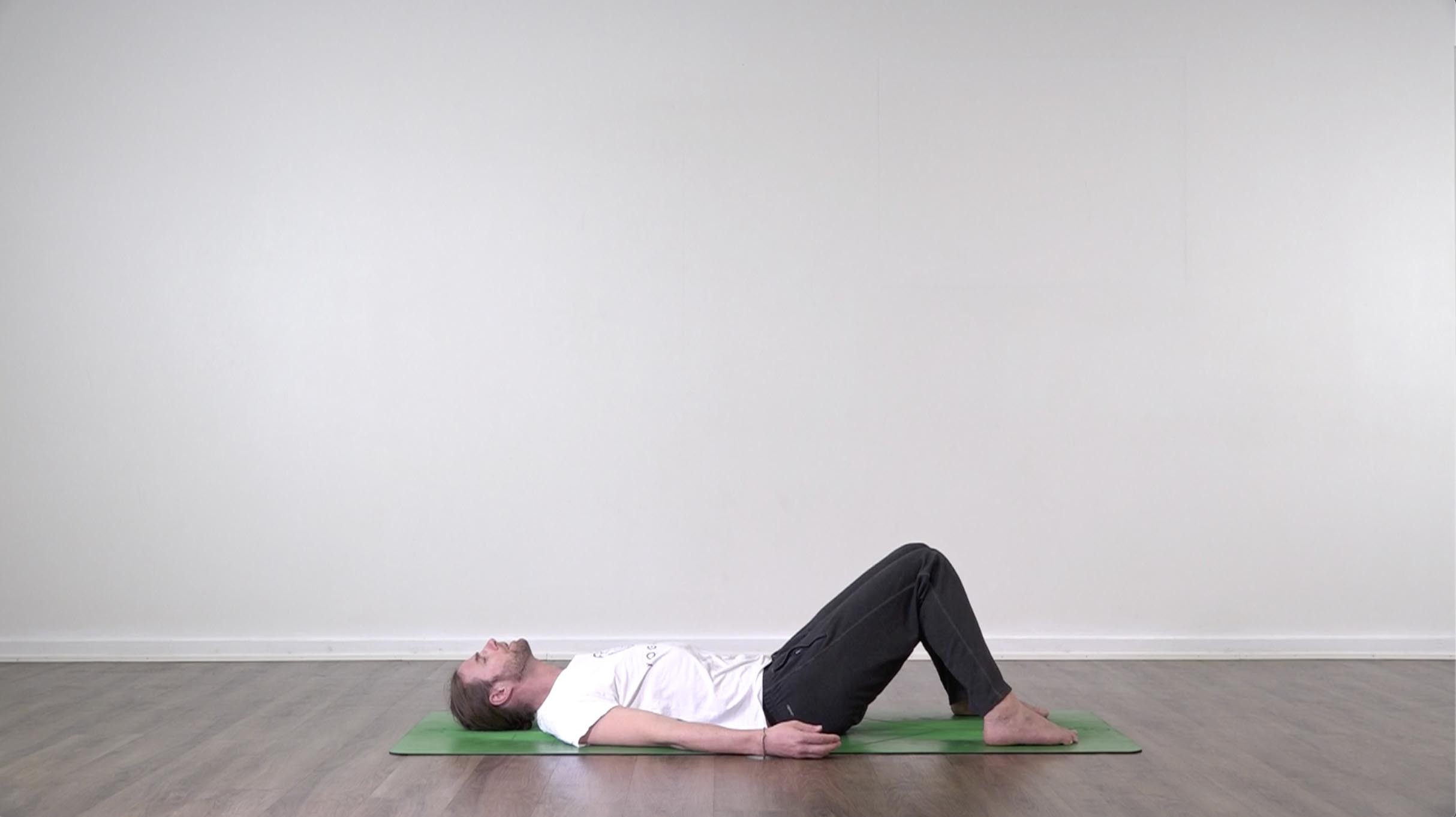 Yoga teacher performing yoga posture on green yoga mat on white background